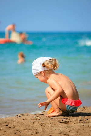  One little girl on the beach dig sand with spades. Bright summer time.の写真素材
