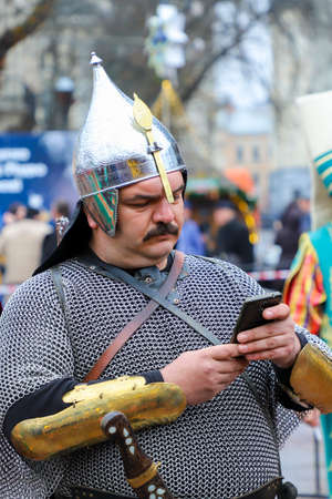 Lviv, Ukraine - January 7, 2018: Man in shining armor with mobile phone. Modern knight.のeditorial素材