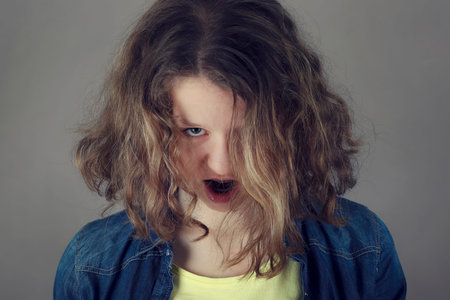 Portrait af angry scary evil young curly hair woman with open mouth.