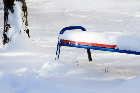 Snow covered bench in the park.