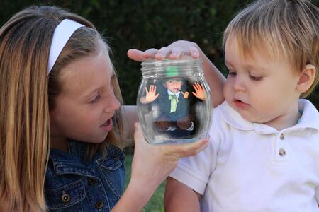 two children amazed by the leprechaun they have caught in a jarの写真素材