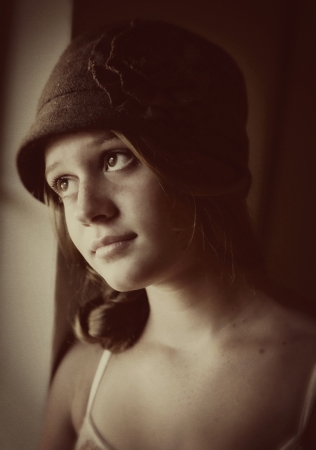 Vintage young girl looking out window dreamingの写真素材