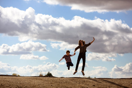 happy children jumping for joy with beautiful cloudy backgroundの写真素材