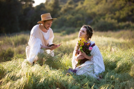 Beautiful romantic couple reading poetry in historical clothingの写真素材