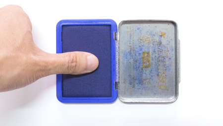 Finger on blue ink stamp pad in front of a white backgroundの写真素材