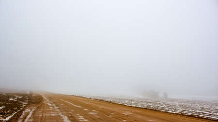bad country road in the fog in the fallの写真素材