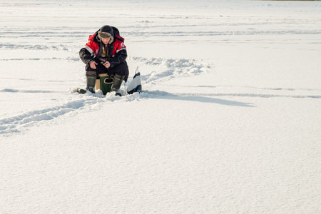 Minsk, Belarus - February 11, 2018: Ice fishing. A man catches fish. Lake Drozdny