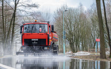 Minsk, Belarus - April 08, 2022: Cleaning sweeper machine washes the asphalt road with water spray.のeditorial素材