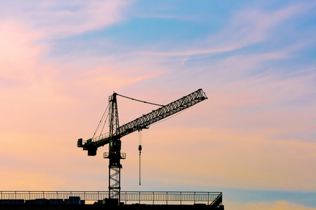 Construction site. Silhouette of a construction crane against the bright evening sky.の写真素材