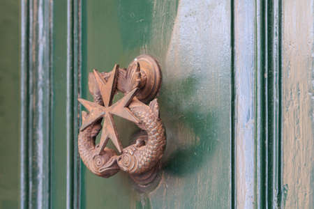 Door knocker with Maltese sign on green backgroundの写真素材