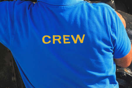 Man with blue polo shirt on his back are written CREW in yellow fontの写真素材