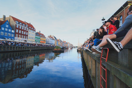 Copenhagen, Zealand Denmark - June 23 2019: Many people sit along the edge of the Nyhavn canal...