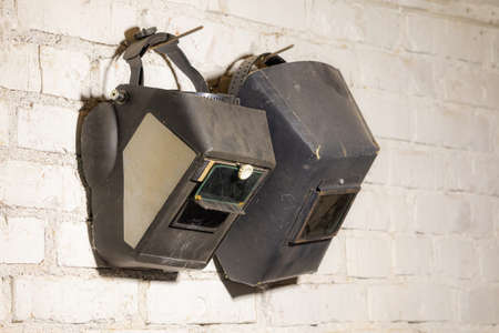 On a white wall hangs two welding masksの写真素材