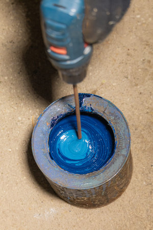 Worker are mixing up old blue paint with drill