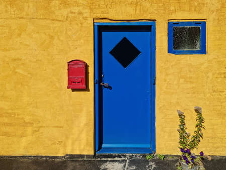 Yellow wall, blue doors, window, red post box - Bornholmの写真素材
