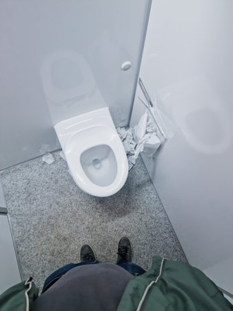 Messy public toilet in Denmark - point of view. Fat man looks down
