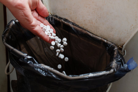 Throwing pills into the garbage - illegal disposal.の写真素材
