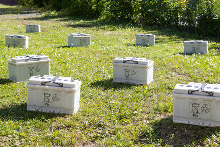 Many Pb lead car batteries on a grass in the nature