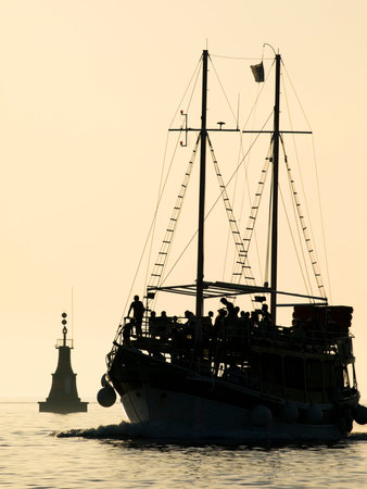 Motor boat full of tourists is going to the harbor after a day trip on the Adriatic sea.