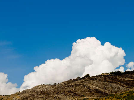 Clouds on top of the hill recently burned by fireの写真素材