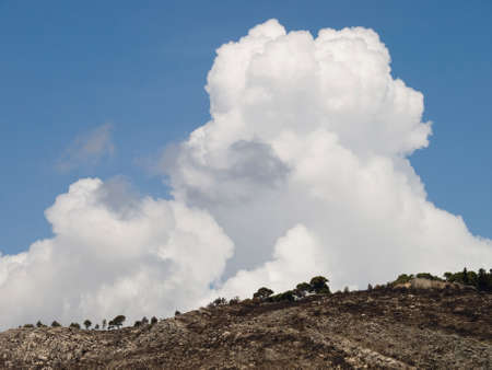 Clouds on top of the hill recently burned by fireの写真素材