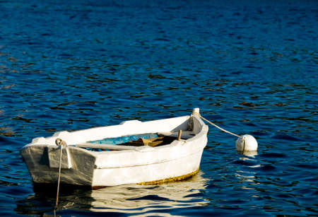 Small and old wooden boat alone on a clear blue sea.の写真素材
