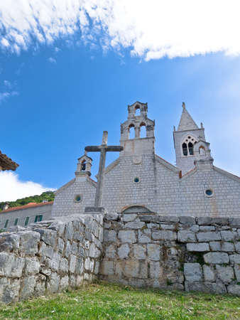 Church with stone cross in front in village Lastovo, Croatiaの写真素材