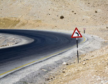 Desert turn on a road in Jordan, with a turning sign.の写真素材