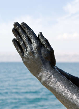 Hand covered with mud from Dead sea, Jordan. Skincare treatment. Use of high depth of field to blur the background.の写真素材