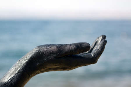 Hand covered with mud from Dead sea, Jordan. Skincare treatment. Use of high depth of field to blur the background.の写真素材
