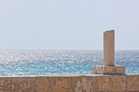 Half of a column on a wall against sea
