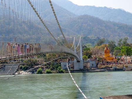 Bridge Laxman Jhula with Pedestrians, on the Holy Ganges river  that flows through Rishikesh (the world capital of Yoga) - the holy city for the Hindus, India.の写真素材