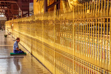 YANGON, MYANMAR - MARCH 1: Prayer praying in front of the giant reclining Buddha at Chaukhtatgyi temple on March 1, 2012 in Yangon, Myanmar.のeditorial素材