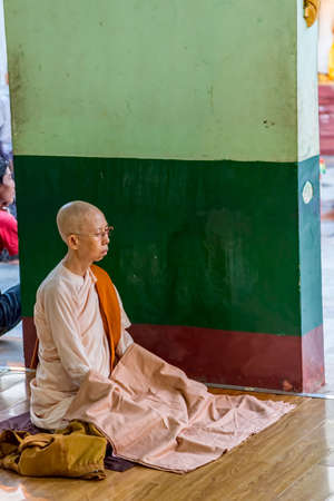 YANGON, MYANMAR - MARCH 1: Buddhist nun pray and meditates in front of The Shwedagon Pagoda on March 1, 2012 in Yangon, Myanmar.のeditorial素材