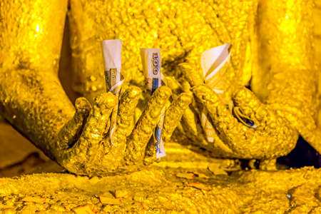 BAGAN, MYANMAR - FEBRUARY 23: Small Buddha statues in Ananda temple are covered with small golden flakes adorned by believers and money bills donated by putting in statue hands on February 23, 2013 in Bagan, Myanmar.のeditorial素材