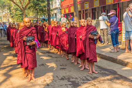 MANDALAY - FEBRUARY 26: Every day procession of Buddhist novices walk to collect alms and offerings is now tourist attraction on February 26, 2013 in Mandalay, Myanmar.のeditorial素材