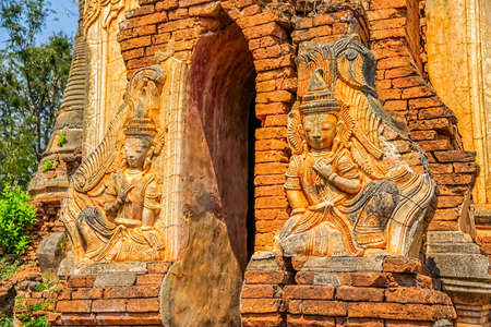 INDEIN, MYANMAR - FEBRUARY 28: Ruined statue at the entrance of the ancient Stupas at Indein overgrown with plants on February 28, 2013 in Indein, Myanmar.のeditorial素材