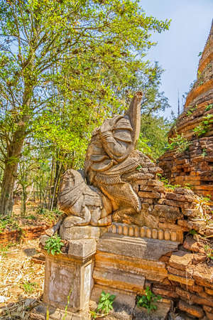 INDEIN, MYANMAR - FEBRUARY 28: Ruined elephant statue at the entrance of the ancient Stupas at Indein overgrown with plants on February 28, 2013 in Indein, Myanmar.のeditorial素材