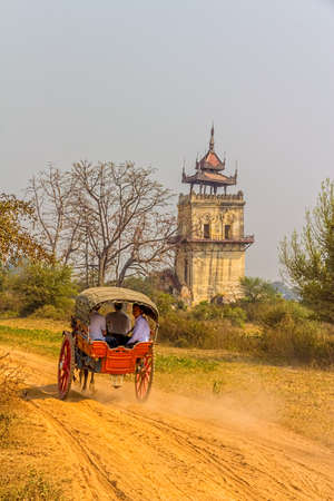 MANDALAY - FEBRUARY 26: Tourists taking horse cart ride to visit Nanmyin or watchtower of Ava on February 26, 2013 in Mandalay, Myanmar.のeditorial素材