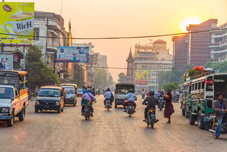 MANDALAY   MYANMAR - FEBRUARY 26 2013   People, cars and bikes on the streets in the center of the city at sunset のeditorial素材