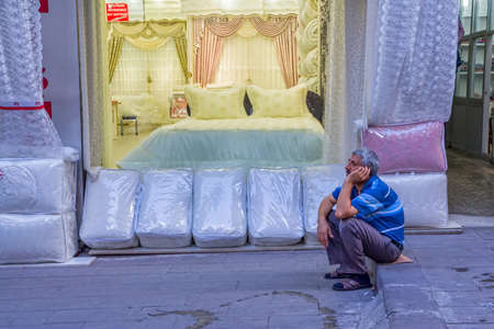 ISTANBUL, TURKEY - SEPTEMBER 26, 2013: Linen salesman talk on the mobile phon in front of his store at The Grand Bazaar (Kapali Carsi) in the afternoon.のeditorial素材