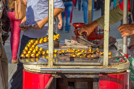 ISTANBUL, TURKEY - SEPTEMBER 28, 2013: A mobile street vendor sells freshly roasted chestnuts on the streets on Istiklal Avenue.のeditorial素材