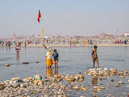 HARIDWAR, INDIA - APRIL 14, 2010: Man calling a group of people raising a flag for recognition at the Kumbh Mela, a mass Hindu pilgrimage of faith.のeditorial素材