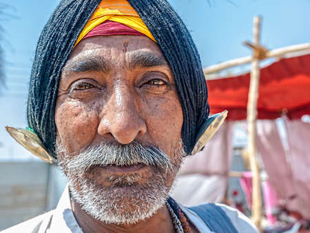 HARIDWAR, INDIA - APRIL 14, 2010: Portrait of a traditionally dressed pilgrim resting in the shade at the Kumbh Mela mass Hindu pilgrimage of faith.のeditorial素材