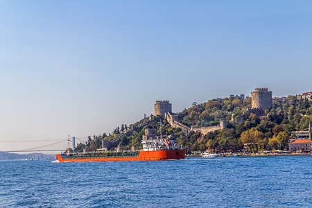 Long red ship sailing in front of the Rumelihisari castle.の写真素材