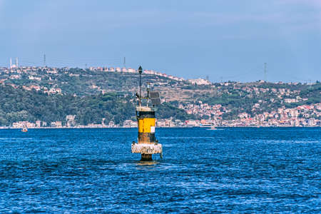 Small sea lighthouse in front of the old finest Ottoman era waterfront houses in Yenikoy. Solar powered.の写真素材