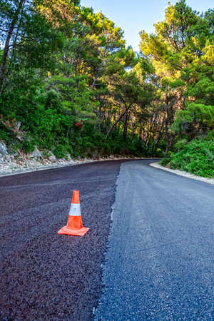Traffic cone on a newly paved road through the forestの写真素材