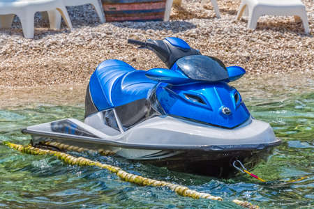 Blue jet ski scooter tied to rope in marine shallow water at the beach.の写真素材