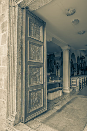 Wooden door with carved reliefs on the St. Petar old christian basilica in Supetar Croatia.の写真素材