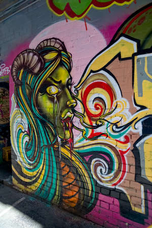 MELBOURNE, AUSTRALIA - MARCH 21, 2015: Colorful graffiti in back alley of downtown, depicts an a woman with sheep horns.のeditorial素材